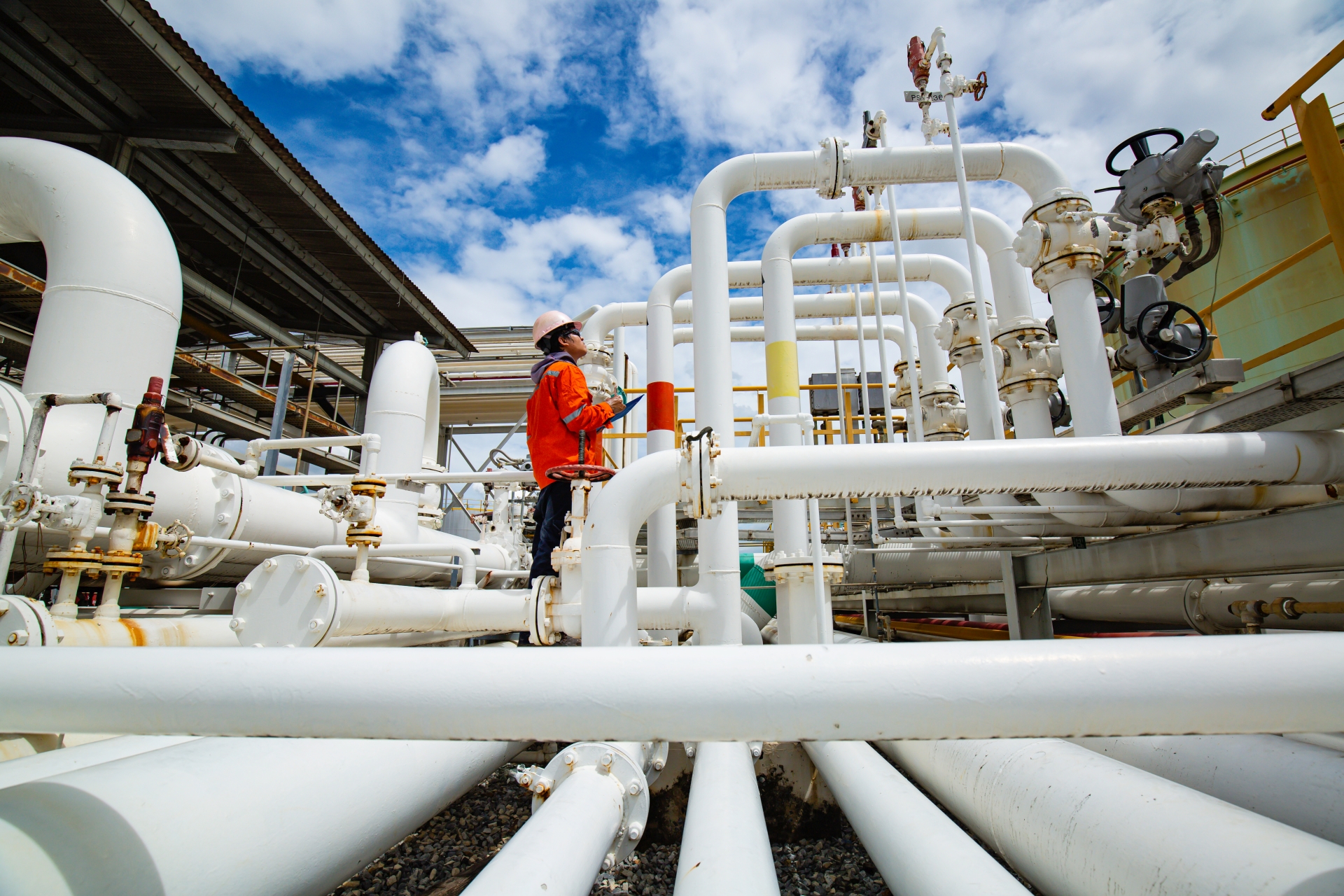 Male worker inspection at steel long pipes and pipe elbow in station oil factory during refinery valve of visual check record pipeline tank oil and gas industry